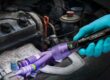 Technician using UV light to detect A/C refrigerant leak in hybrid vehicle